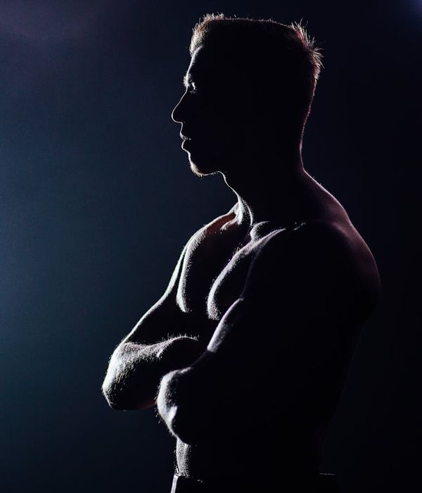 Hombre realizando un ejercicio dinámico de fuerza de core en un estudio oscuro.